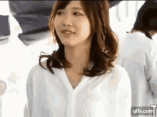 a woman in a white shirt is standing in front of a crowd of people .