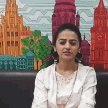 a woman sitting in front of a painting of buildings