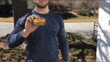 a man in a blue shirt is holding a small hamburger