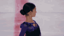 a female figure skater in a purple dress is dancing on the ice
