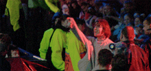a crowd of people are gathered in a dark room with a man wearing a sweater that says bmw on it