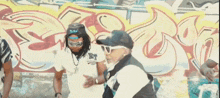 a group of people are dancing in front of a graffiti wall .