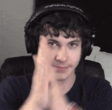 a young man wearing headphones is sitting in a chair and clapping his hands .
