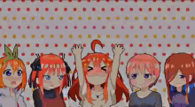 a group of anime girls are standing next to each other in front of a polka dot wall .