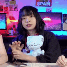 a girl is sitting at a table with a stuffed dinosaur and a sign that says spam