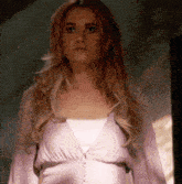 a woman in a pink dress is standing in front of a mirror and looking at the camera .