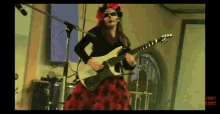 a woman in a red dress is playing a guitar in front of a microphone and a sign that says rock
