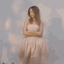 a woman in a plaid dress is standing with her arms crossed