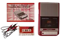 a nintendo data recorder sits next to a cassette tape and a manual