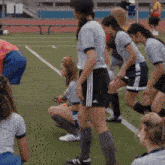 a group of female soccer players are squatting down on the field