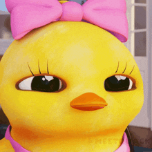 a close up of a yellow duck with a pink bow