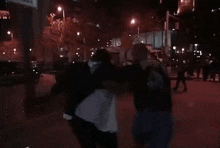 a group of people are standing on a sidewalk at night .
