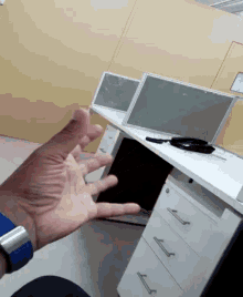 a man 's hand is reaching out towards a desk in an office