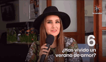 a woman in a black hat is holding a microphone in front of a sign that says las estrellas