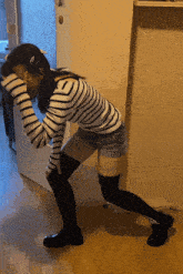 a woman wearing a striped shirt and shorts is kneeling down