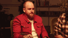 a man in a red jacket is sitting in a chair