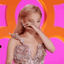 a woman in a dress is covering her face with her hand and making a funny face .