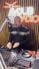 a man is playing music in front of a neon sign that says dub radio