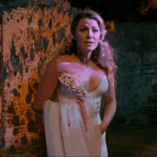 a woman in a white dress with flowers on it is standing in front of a stone wall
