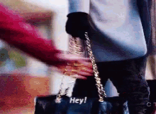 a woman is holding a purse and says hey .