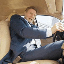a man in a suit and tie is driving a car with a sun visor on the roof