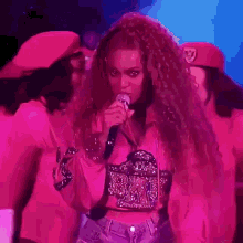 a woman is singing into a microphone while wearing a pink outfit .