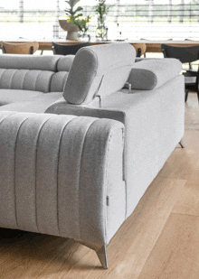 a grey couch is sitting on a wooden floor in a dining room