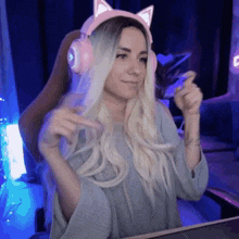 a woman wearing headphones with cat ears is sitting in front of a computer screen .