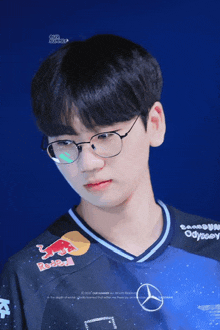 a young man wearing glasses and a blue red bull shirt