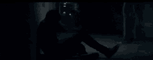 a man is sitting on the ground in a dark alleyway .