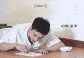 a man is laying on the floor writing on a piece of paper