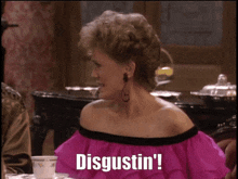 a woman in a pink dress is sitting at a table and says disgustin '