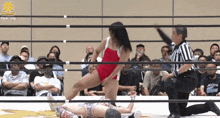 a woman in a red leotard is wrestling another woman in a ring