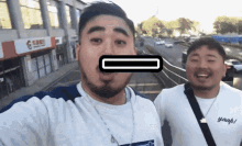 two men are posing for a selfie with one wearing a yaah t-shirt