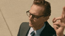 a man in a suit and tie with glasses looks at something