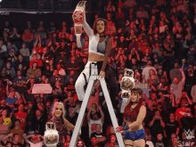 a female wrestler stands on a ladder holding a wrestling championship belt