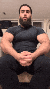 a man with a beard is sitting with his legs crossed
