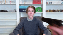 a young man sitting in a chair with a ps4 in the background