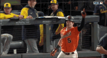 a baseball player with the number 5 on his jersey stands on the field