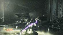 a video game screen shows a person holding a purple sword in a dark room