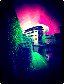 a painting of a building with a pink and green sky