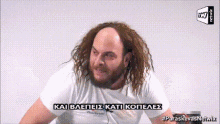 a man with long hair and a beard is wearing a white t-shirt that says paraskevas network