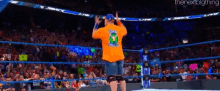 a wrestler is standing in a wrestling ring giving a high five to the crowd .