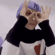 a person wearing a purple hat and a black and white sweater is making a funny face .