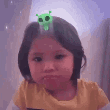 a little girl is wearing a green skull headband on her head .