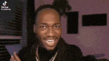 a man with dreadlocks is making a funny face while wearing a gold chain .