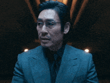 a man with glasses and a suit looks at the camera