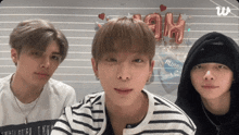 three young men are posing for a picture in front of a sign that says " ah "