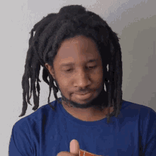 a man with dreadlocks is wearing a blue shirt and holding something