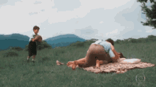 a man and woman laying on a blanket in the grass